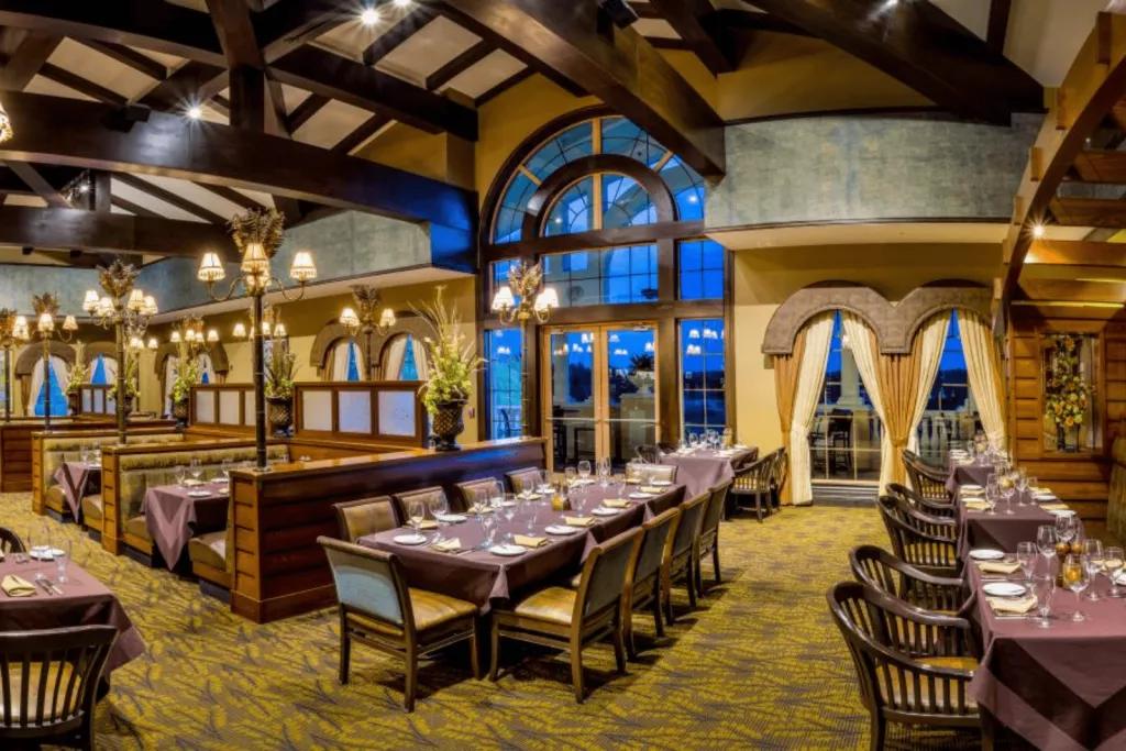 The interior of a restaurant with lots of tables including booth seating in front of large arched windows