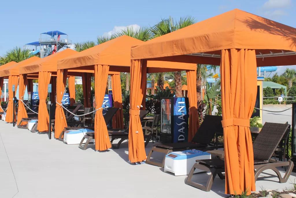 A row of orange cabanas with deck chairs, coolers and drinks machines inside