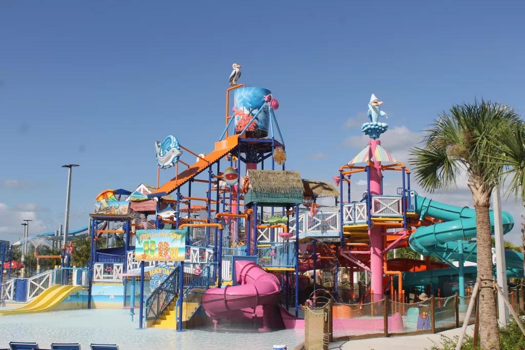 A children's water playground with multiple coloured water slides and tip buckets