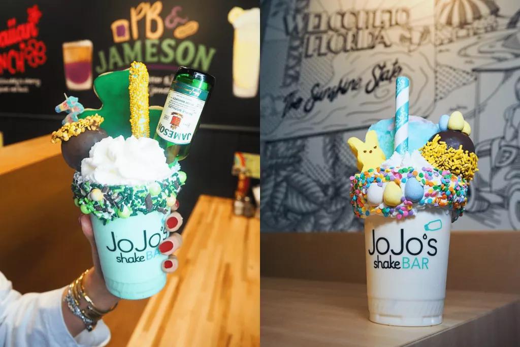 Two large milkshakes topped with whipped cream, candy floss, chocolates and sprinkles