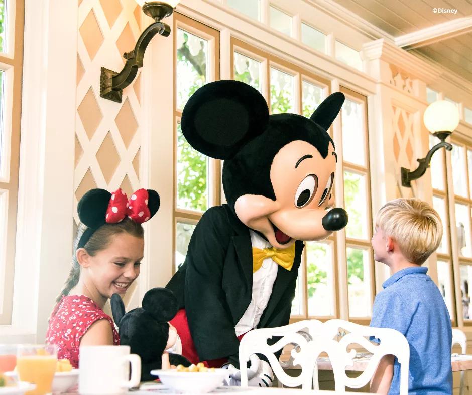 A photo of Mickey Mouse with guests at character dining
