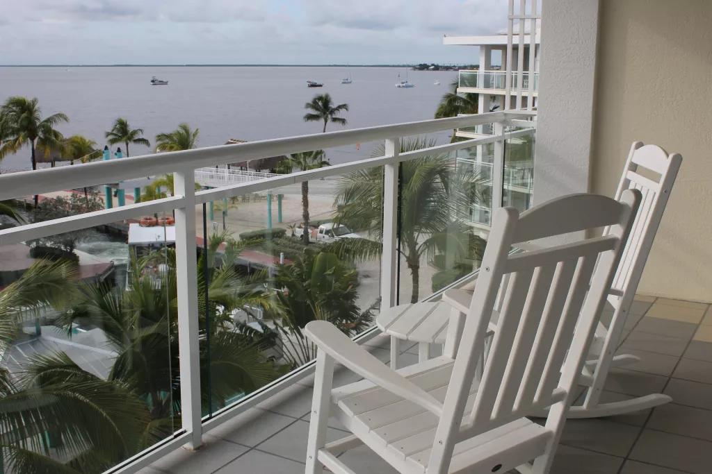 Two white wooden rocking chairs on a balcony looking out over the ocean