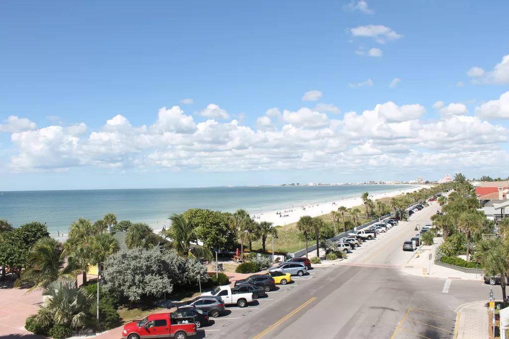An aerial view looking down across miles of sandy beach with a road adjacent to it