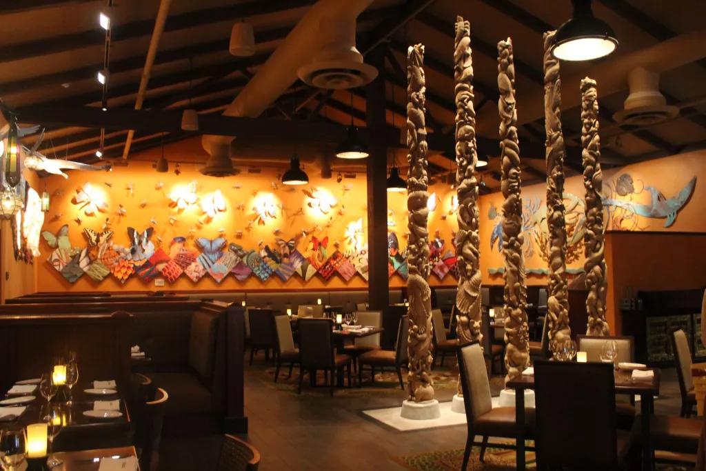 An empty restaurant with butterflies and animal prints on the wall and pillars designed to look like they are made of shells