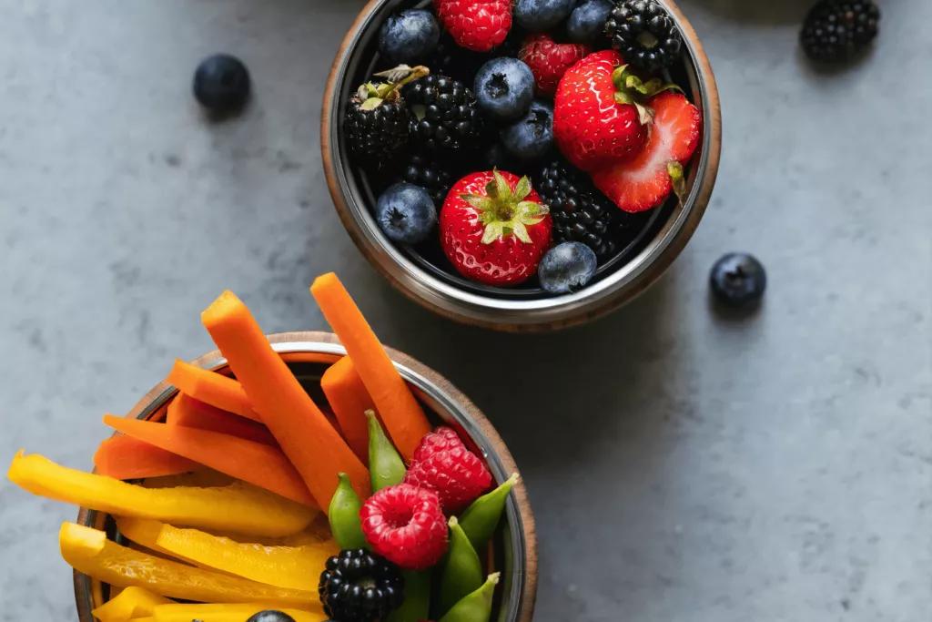 A bird's eye view of a pot of berries and a pot of cut up vegetables
