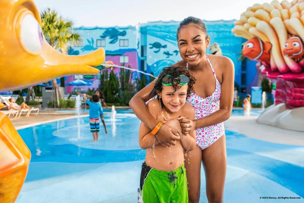 A young boy and girl standing in a splash pad themed after Finding Nemo
