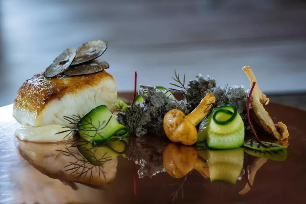 A plate of grilled fish with vegetables and herbs