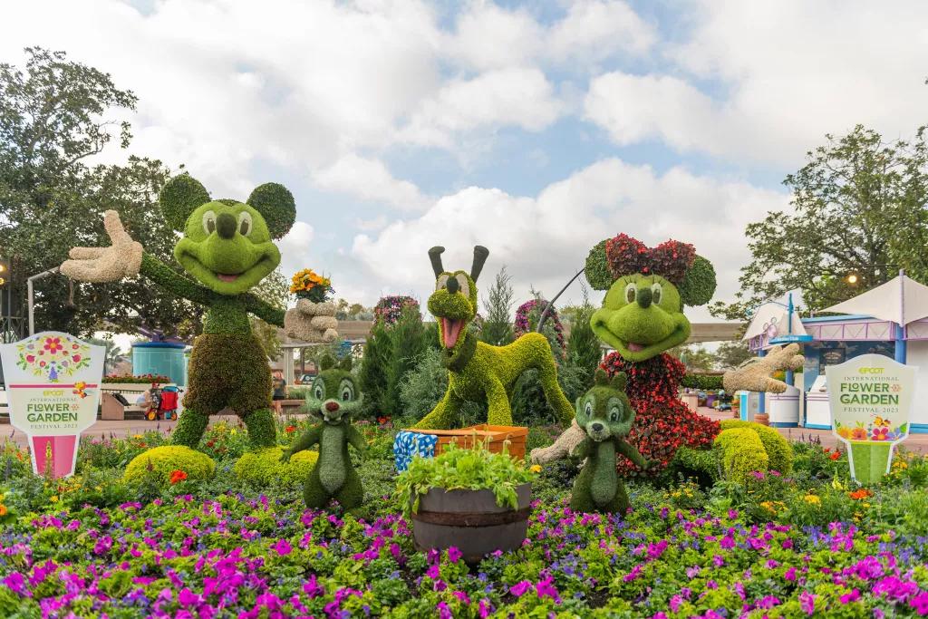 Topiaries shaped like Mickey Mouse, Minnie Mouse and Pluto in a flower bed