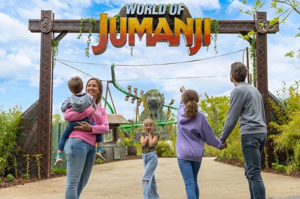 A family standing in front of a sign reading World of Jumanji. One child is holding her face as if in shock