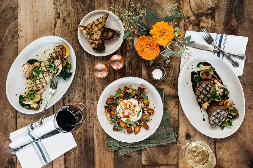 A bird's eye view of a table set with dishes of food, glasses of wine and table settings