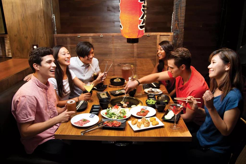 A group of friends sat round a table eating Japanese food