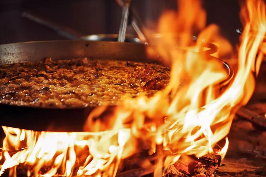 A large pan of paella being cooked over an open flame