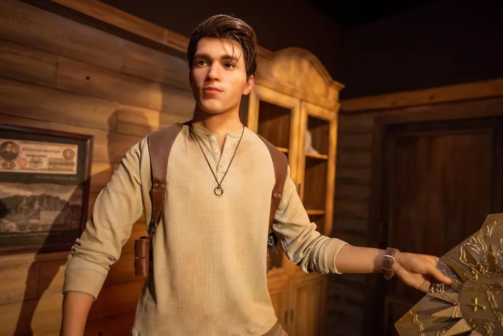 A wax figure of a young man wearing a beige top and holding a map