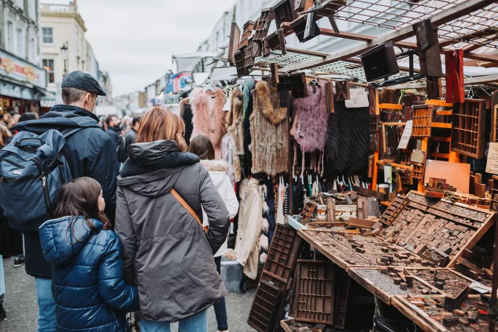Eine Familie mit Kind läuft über den Portobello Road Market in London