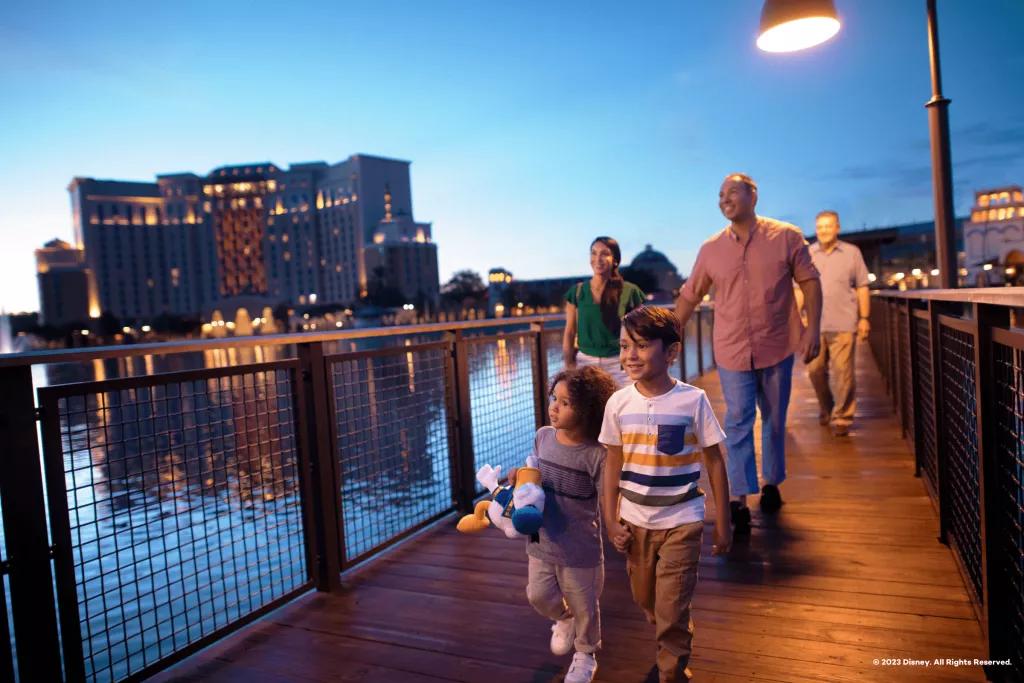 A family walking along a wooden bridge with Coronado Springs in the background