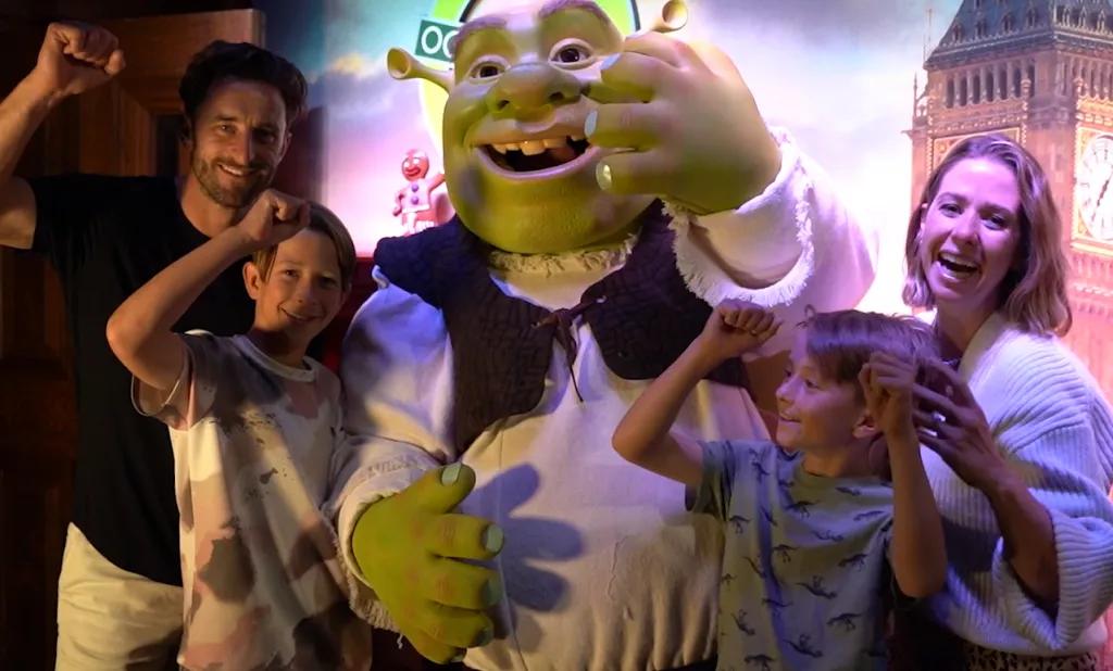 Eine lachende Familie steht mit der Filmfigur Shrek in Shrek's Adventure