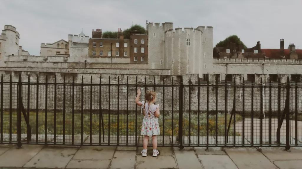 Ein kleines Mädchen steht an einem Zaun vor dem Tower of London