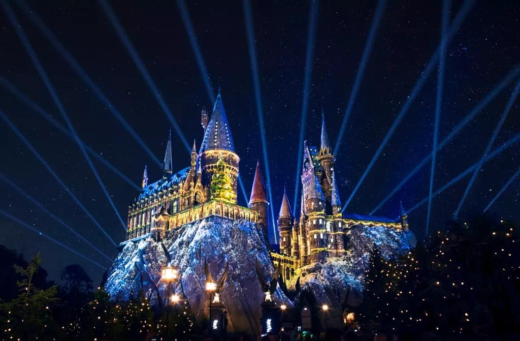Hogwarts Castle lit up in the dark with yellow and blue projections
