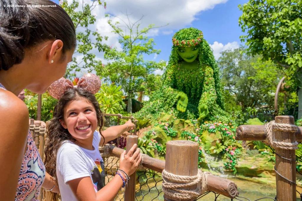 A girl looking back at a woman while pointing to a large figure of Te Fiti from the film Moana