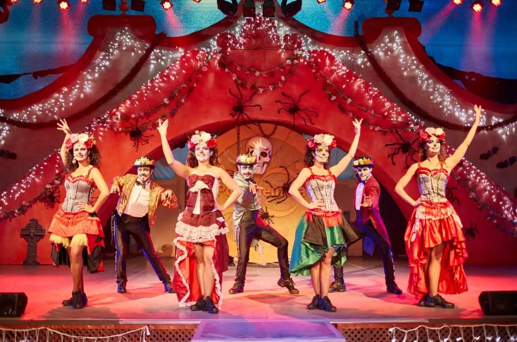 Performers posing on stage wearing Mexican costumes and Day of the Dead face paint
