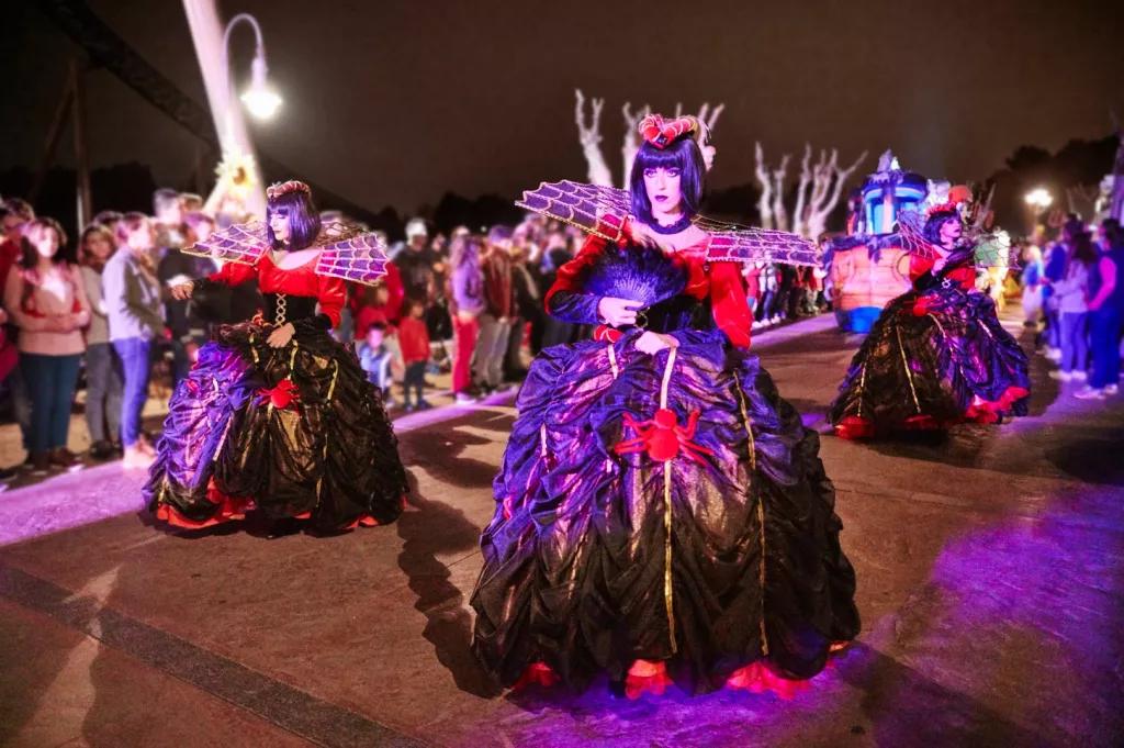 Parade performers dressed in large hooped dresses with spider details