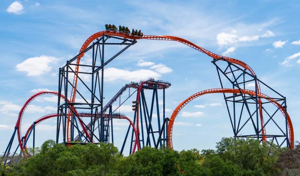 Two rollor coasters with intertwining tracks in front of a blue sky