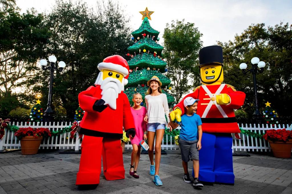 Three children posing in front of a LEGO Christmas tree with LEGO santa and a toy soldier
