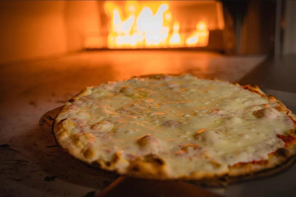 A cheese pizza in a wood fired pizza oven
