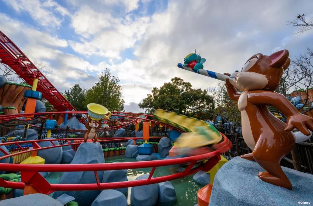 A rollercoaster train going round a red track next to models of Chip and Dale