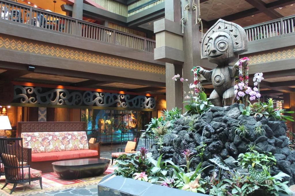 A tiki statue on top of a rock and flower formation in the middle of a hotel lobby