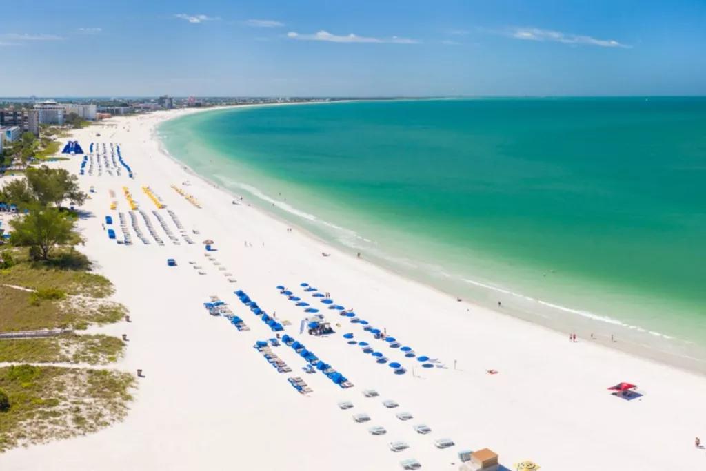 An aerial view along a white sandy beach lined with sun loungers
