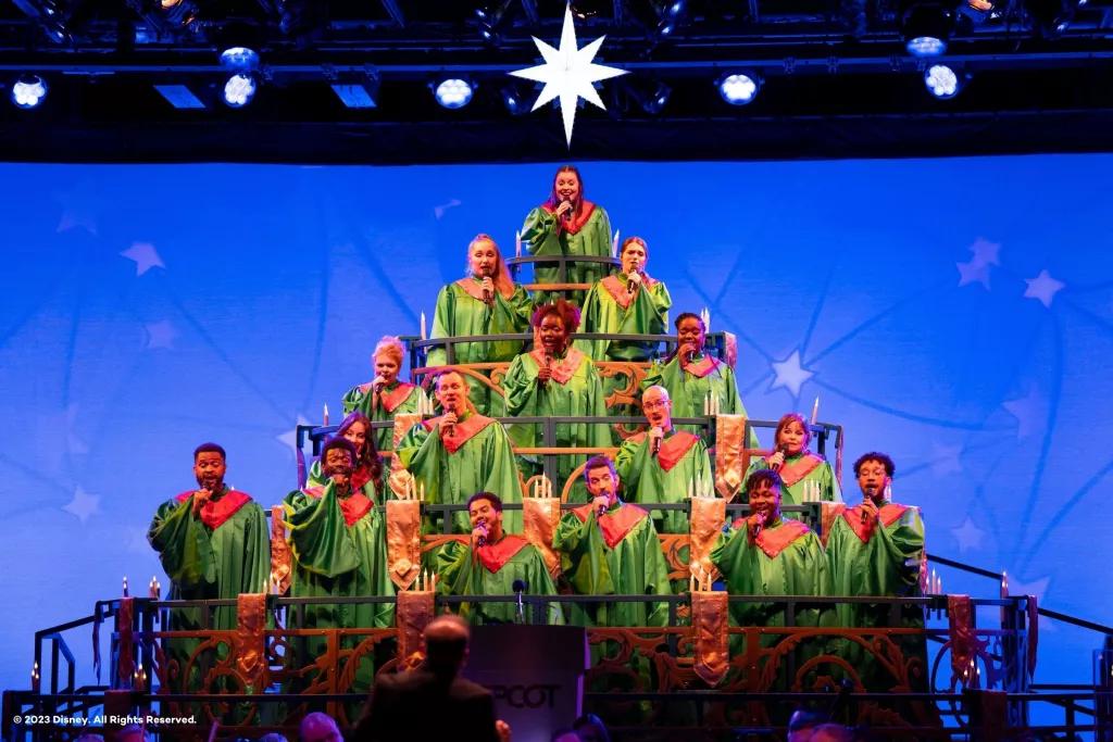 A choir dressed in green robes standing in a pyramid formation to look like a Christmas tree