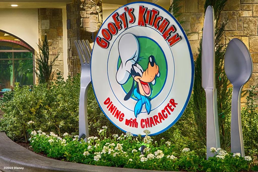 A sign for Goofy's Kitchen shaped like a dinner plate with Chef Goofy in the centre next to large cutlery