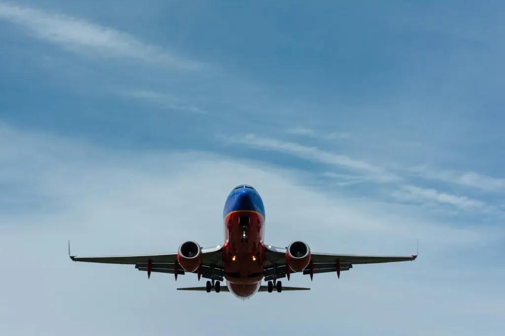 Looking up at a plane flying through a blue sky