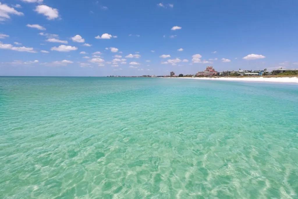 A wide expanse of clear turquoise water with a shoreline in the background
