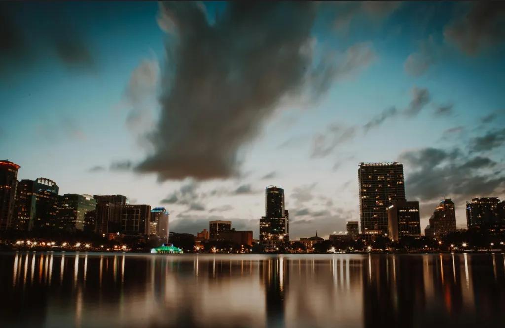 A lake leading up to a city skyline with the sun setting in the background