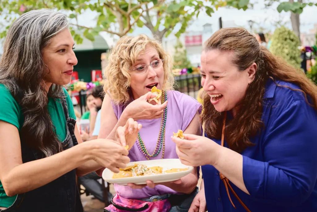 Three women laughing while sharing a plate of food