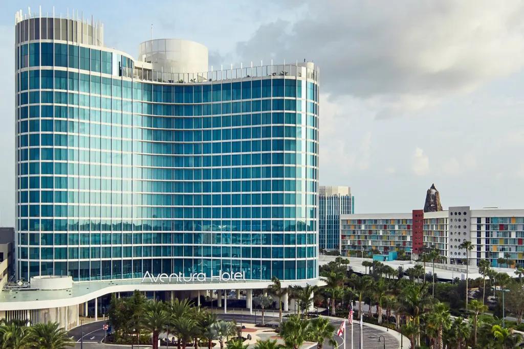 A tall hotel covered in glass panels with a rooftop bar on top