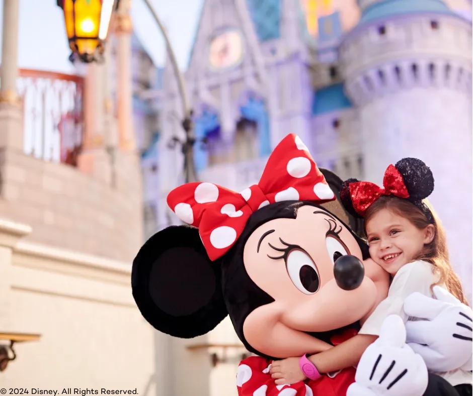 Minnie Mouse hugging guest in front of Cinderella's castle