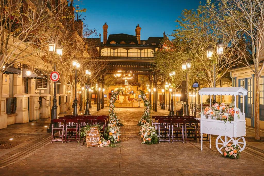 Rows of benches and a floral wedding arch in front of a facade of Paris at dawn