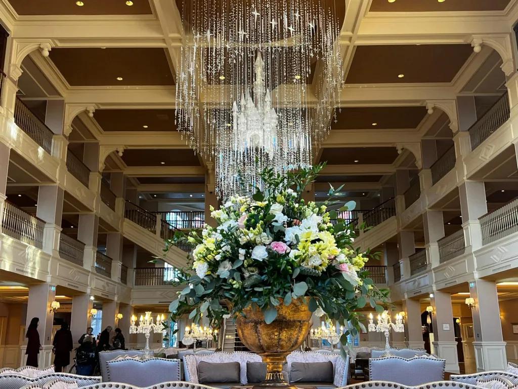 A bouquet of flowers on a side table in a large hotel lobby with a 