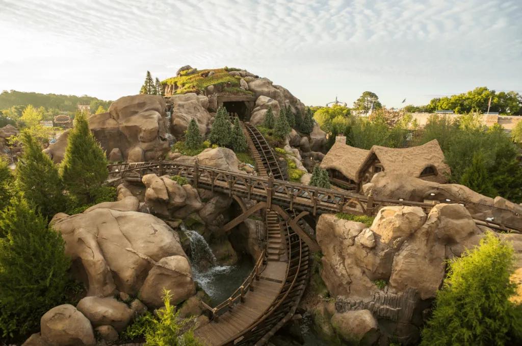 A rollercoaster track designed to look like it is coming out of a mine shaft on a rocky mountain