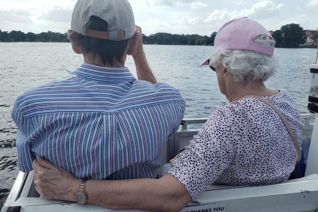 An older couple on a boat tour. The woman's arm is around the man's back