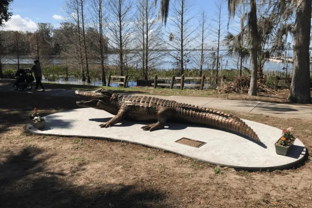 A bronze statue of an alligator on a grass bank