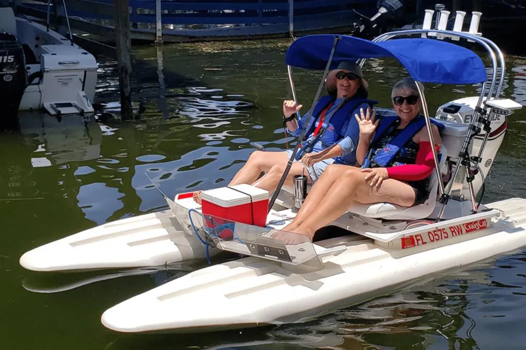 Two women waving at the camera from a small boat