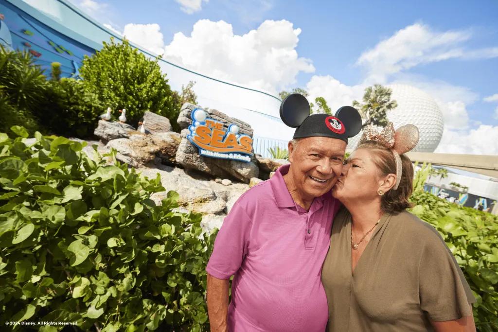 An woman kissing man on the cheek in front of The Seas with Nemo and Friends