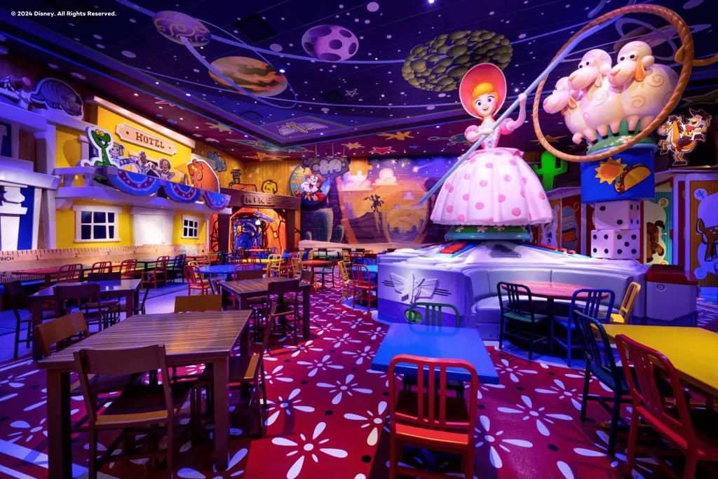 An empty restaurant filled with tables and chairs surrounding a large statue of Bo Peep from Toy Story