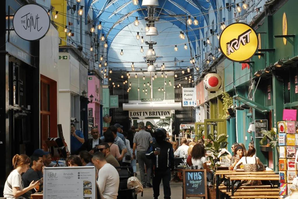 People sat at tables outside restaurants in Brixton Market