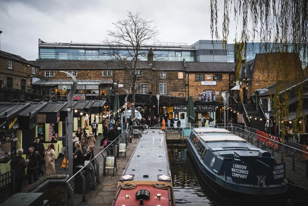 People browsing market stalls in Camden Market next to the canal