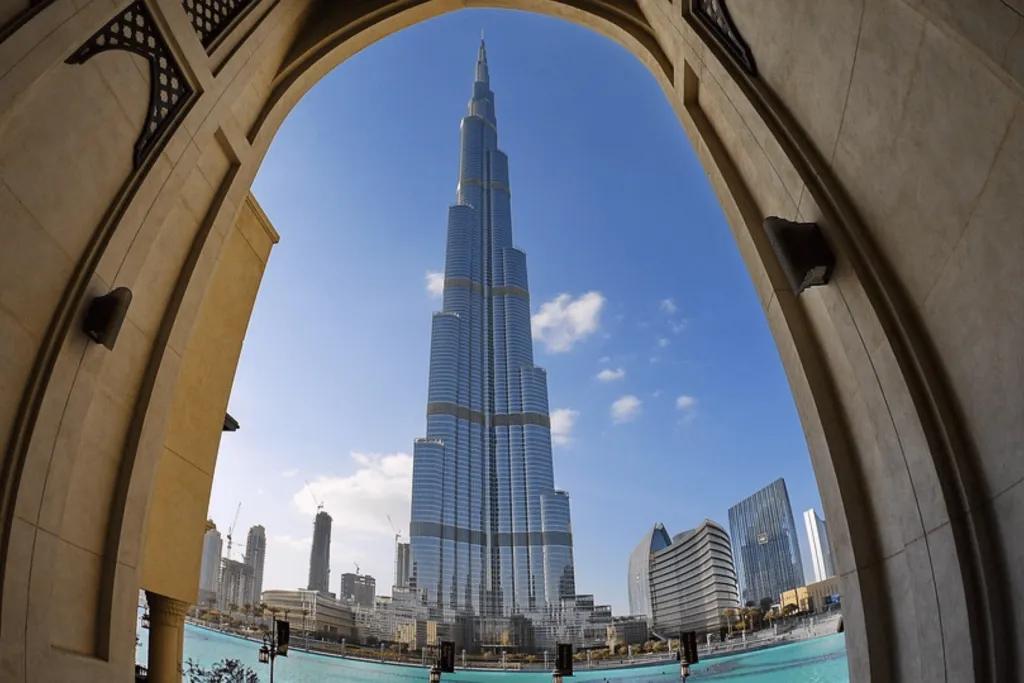 A view of the Burj Khalifa tower through an archway and below there is a river. The Burj Khalifa is the world's tallest building made purely of glass windows in a triangle shape.